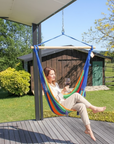 Woman sitting in a colorful hammock on a deck with a scenic background