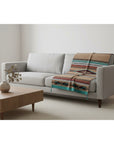 Sofa with a patterned throw blanket in a minimalistic living room.
