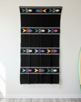 Black towel with colorful patterns hanging on a white wall