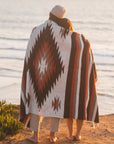 Couple wrapped up in blanket watching ocean