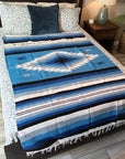 Blue striped blanket on a bed with pillows in a bedroom setting
