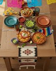 Dining table set with Mexican food including tacos, guacamole, and salsa on a wooden table.