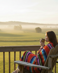 woman sitting on deck chair overlooking farmland on misty morning