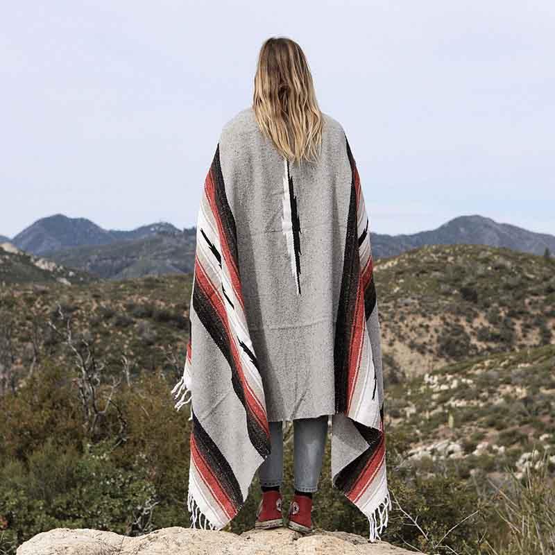 Women wrapped in Mexican blanket overlooking desert