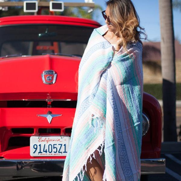 Woman standing by car in California wrapped in Mexican beach blanket