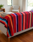 Colorful striped blanket draped over a white sofa in a living room.