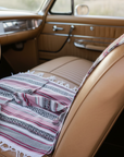 Vintage car interior with a patterned blanket draped over the seat