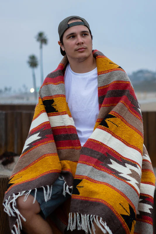 Man wrapped in a colourful patterned blanket outdoors