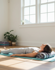 Woman lying on a yoga mat in a bright room with large windows