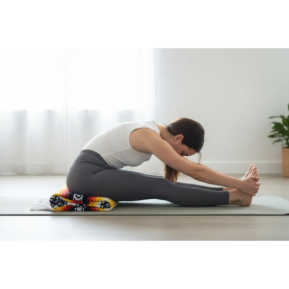 woman stretching in yoga pose with Mexican blanket under thighs