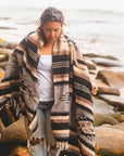woman wearing blanket while exploring beach setting