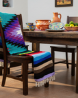 Colorful striped blanket draped over a wooden chair in a dining room setting.