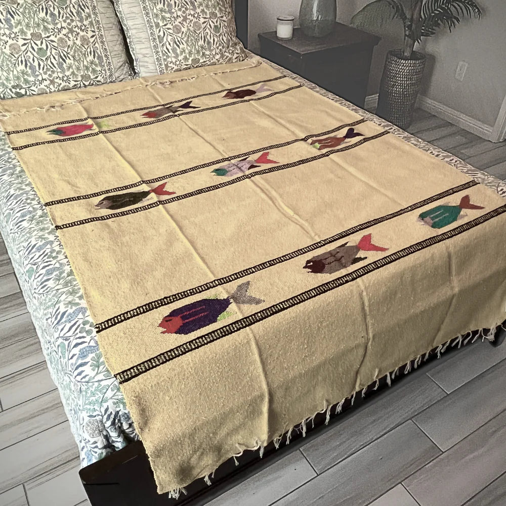 Beige blanket with fish patterns on a bed in a bedroom setting