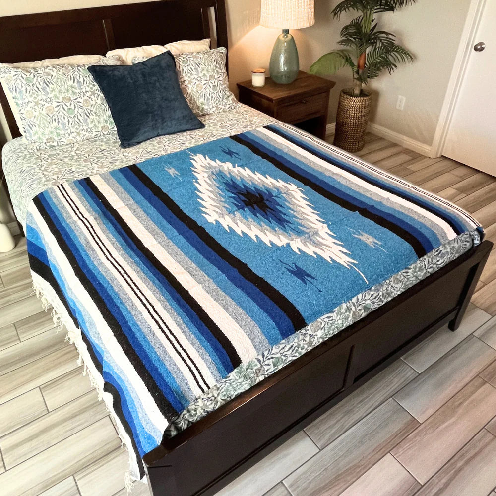 Bed with a blue and white patterned blanket in a bedroom setting.