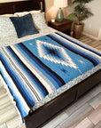 Bed with a blue and white patterned blanket in a bedroom setting.