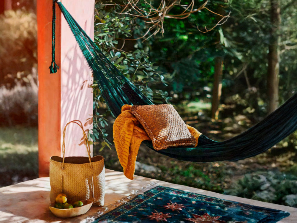 Green hammock with a blanket and pillow in a forest setting