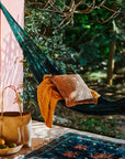 Green hammock with a blanket and pillow in a forest setting