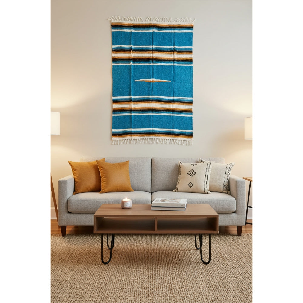 Living room with a gray sofa, wooden coffee table, and a colorful tapestry on the wall.