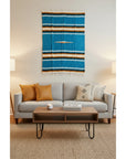 Living room with a gray sofa, wooden coffee table, and a colorful tapestry on the wall.