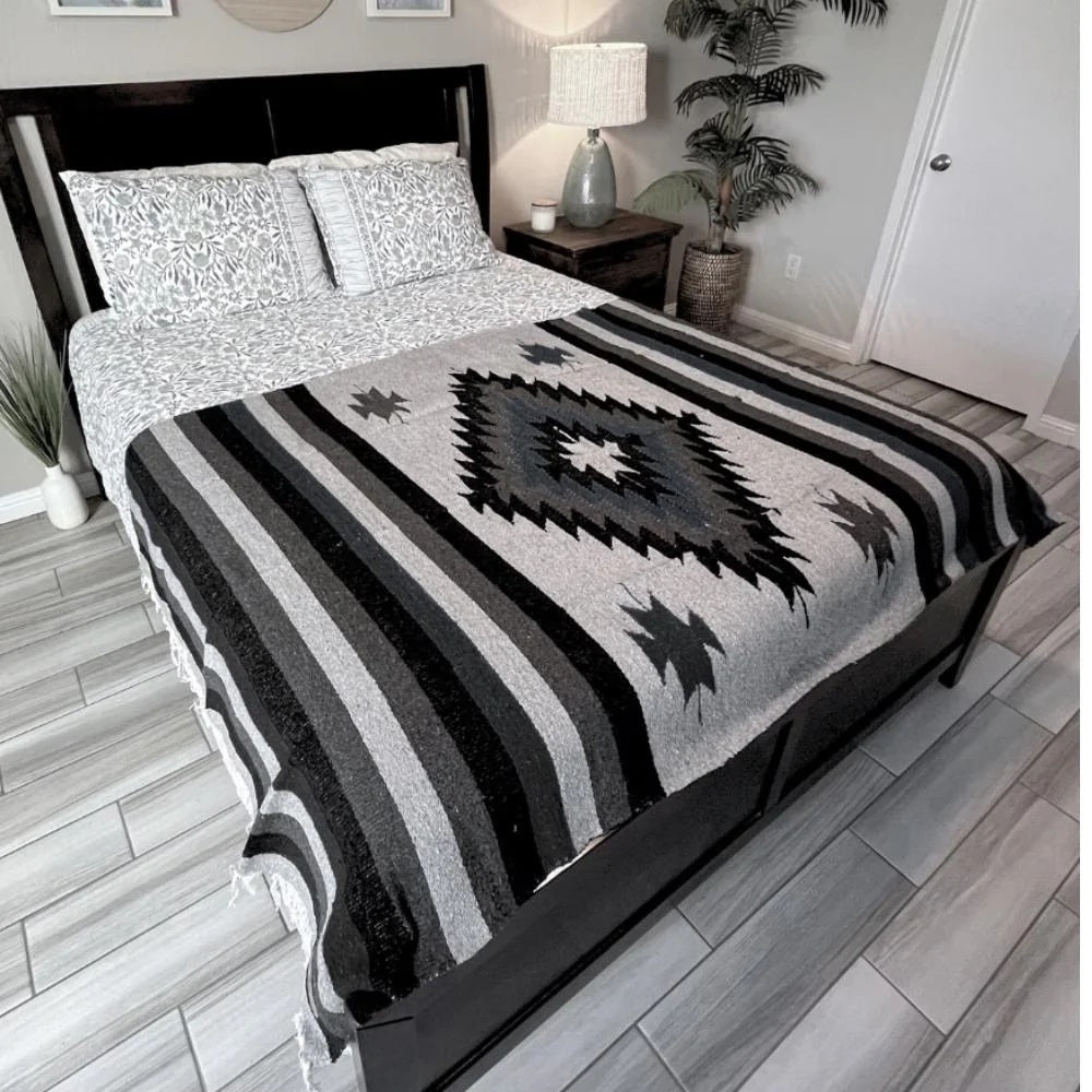 Bed with a black and gray patterned comforter in a bedroom setting.