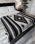 Bed with a black and gray patterned comforter in a bedroom setting.