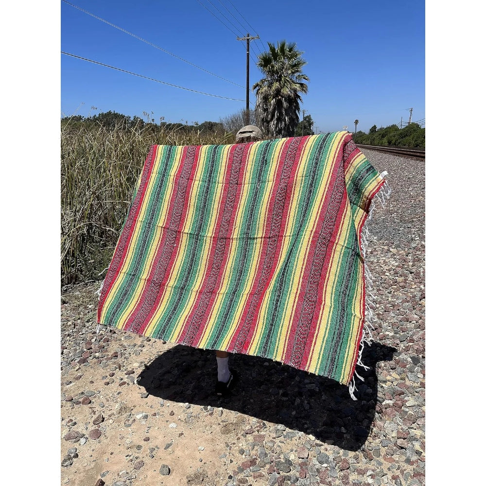 Colorful striped blanket on a rocky surface with a clear blue sky.