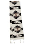 A wool table runner with a Southwestern Mexican design, featuring geometric patterns in black, white, and other colors.