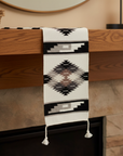 Decorative blanket with geometric pattern draped over a wooden mantel.