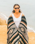 Woman wrapped in Mexican pattern blanket at the beach