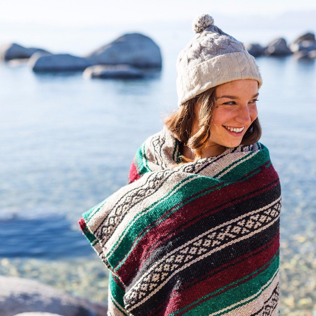 Woman wrapped in a patterned blanket by a body of water