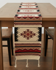 Patterned table runner on a wooden table with chairs in a room.