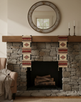 Stone fireplace with wooden mantel, decorative towels, and a round mirror above.