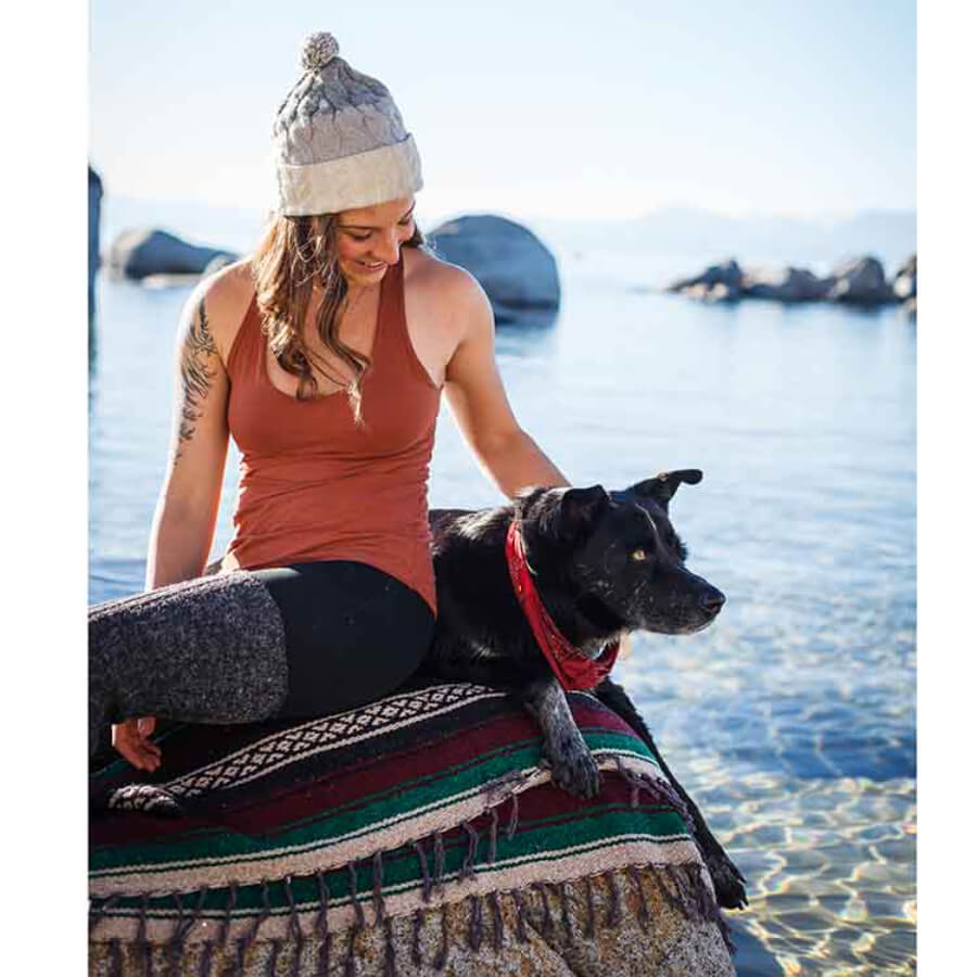 Woman and dog resting on Mexican striped blanket at beach