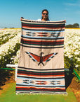 Large Mexican style blanket being held up in garden