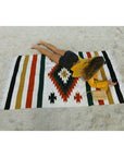 woman lying on white Saltillo Mexican blanket at the beach