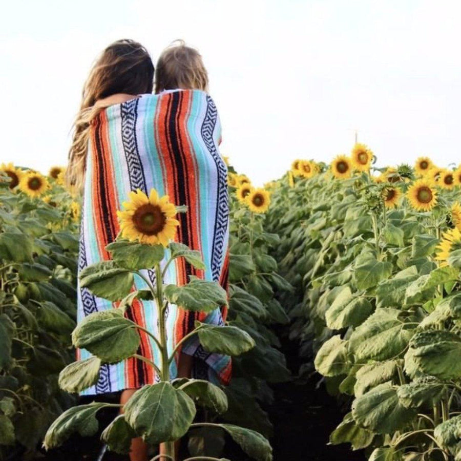 Mum and child in sunflower field with Mexican blanket