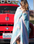 Woman standing by car in California wrapped in Mexican beach blanket