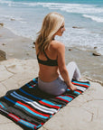 Women sitting on Mexican blanket at beach