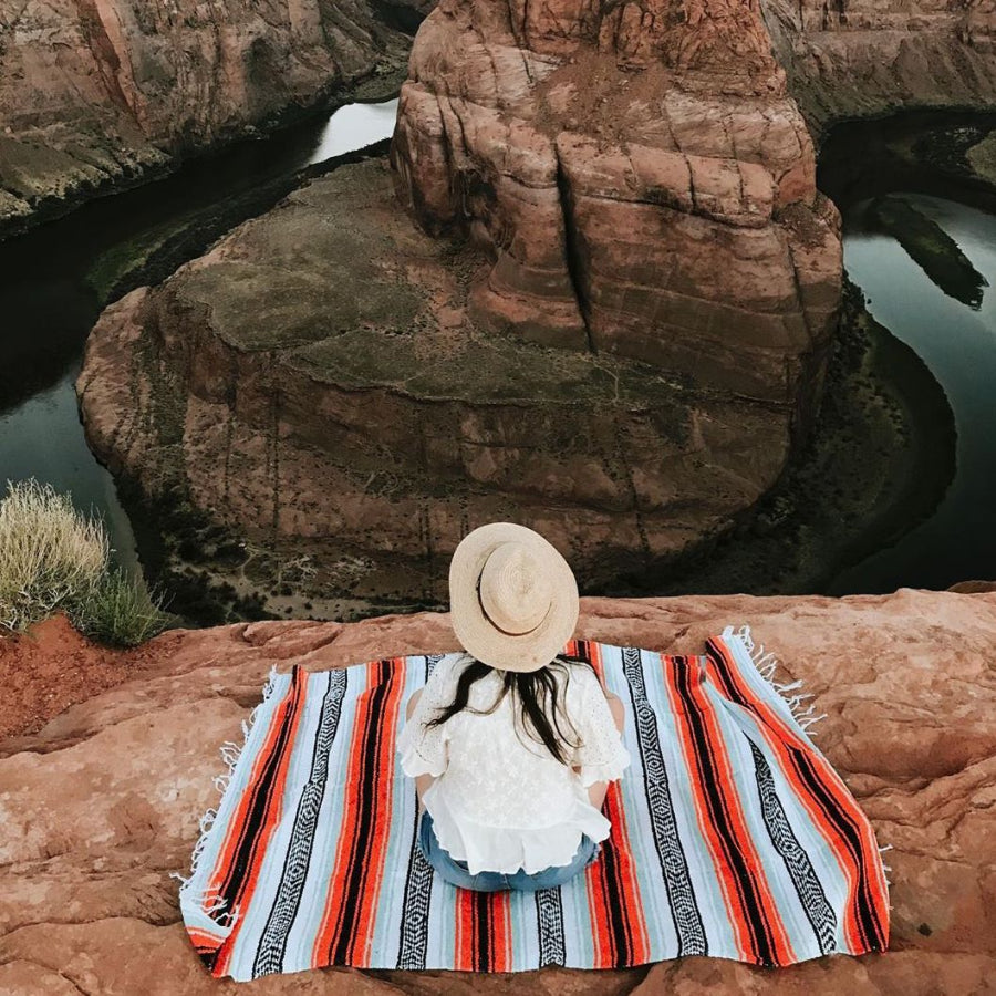 Woman on Mexican picnic rug overlooking river