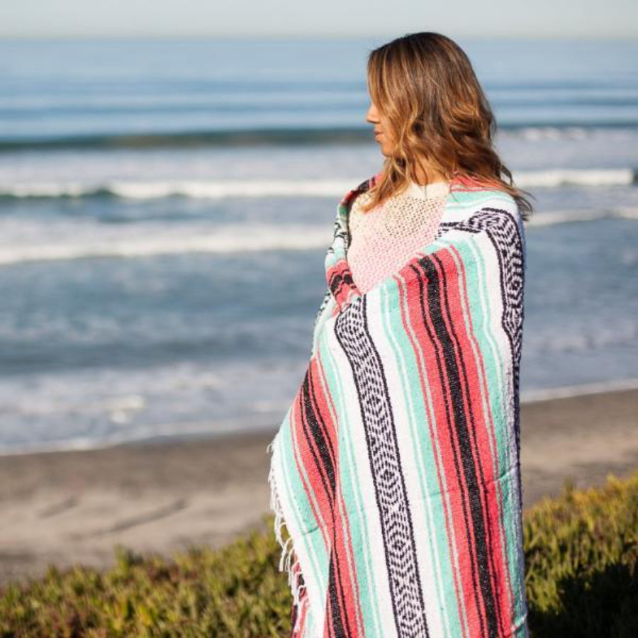 Woman wrapped in Mexican falsa blanket at beach