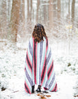 Woman in snow wrapped in Mexican blanket