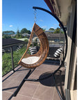 Curved chair hammock stand with egg hanging nest on balcony